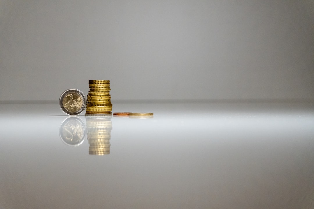 a-stack-of-coins-sitting-on-top-of-a-reflective-surface-dh1dabikjyo